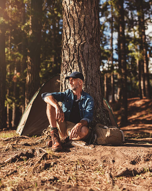 idoso sentado sozinho na sua parque de campismo - forest sitting men comfortable imagens e fotografias de stock