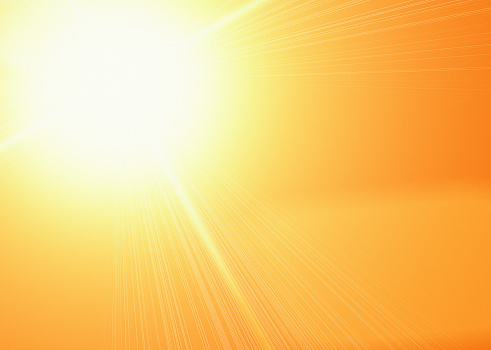 Blazing sun on a background of gold deepening to orange, with radiating rays and lens flare. Ample copy space.