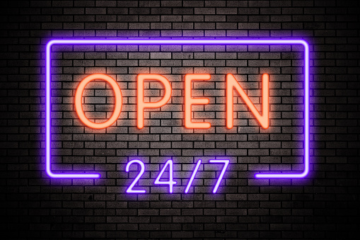 Open 24 hours neon light on brick wall.