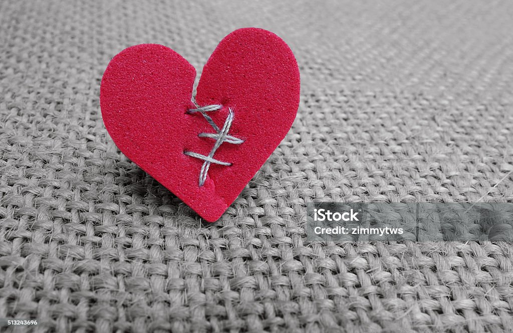 broken hearted Broken red heart with white thread stitches Broken Heart Stock Photo
