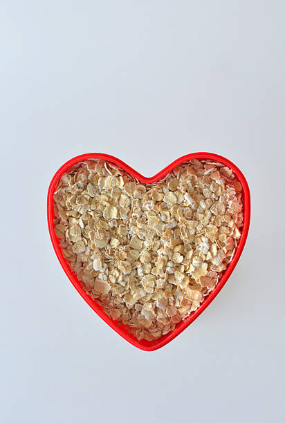 zarte flocken in herz - oatmeal oat heart shape rolled oats stock-fotos und bilder