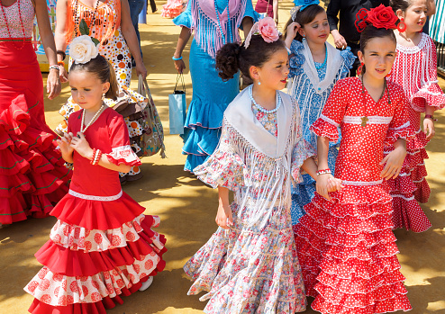 Seville, Spain - April 23, 2015: Spanish girls in traditional dress walking alongside Casetas at the Seville Fair. The Seville Fair \