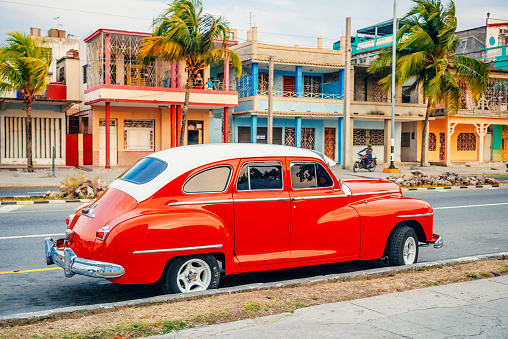 Red American car parking at a street of Cienfuegos, Cuba