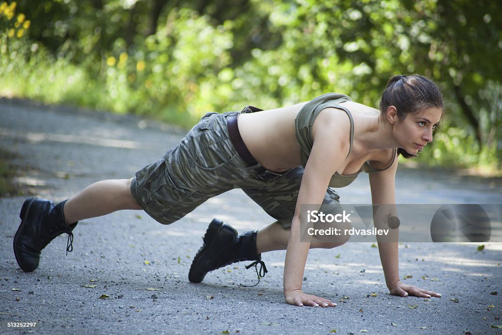 Beautiful military woman training in park - pushups Military woman training in park. Outdoors portrait. Active Lifestyle Stock Photo