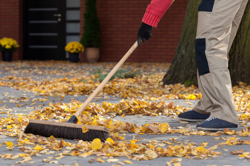A man sweeping leaves from his terrace