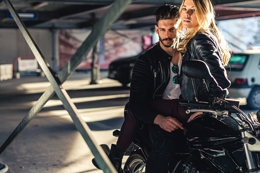 Stylish couple sitting on their motorcycle.