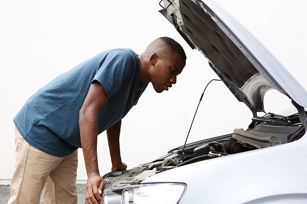 istock African guy looking under hood of broken down car 513253678