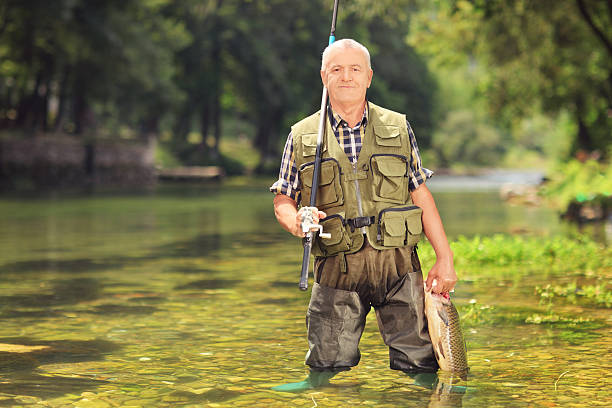 istock Mature fisherman holding fish in a river 513274013