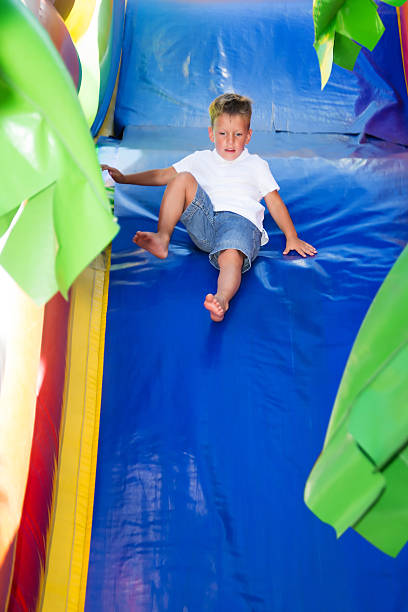 mały chłopiec przesuwne na nadmuchiwane hill - inflatable slide sliding child zdjęcia i obrazy z banku zdjęć