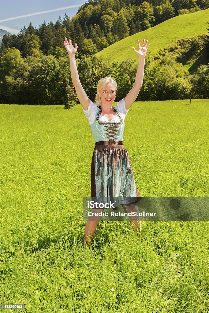 Mujer rubia en un dirndl es feliz en un prado verde - Foto de stock de Adulto libre de derechos