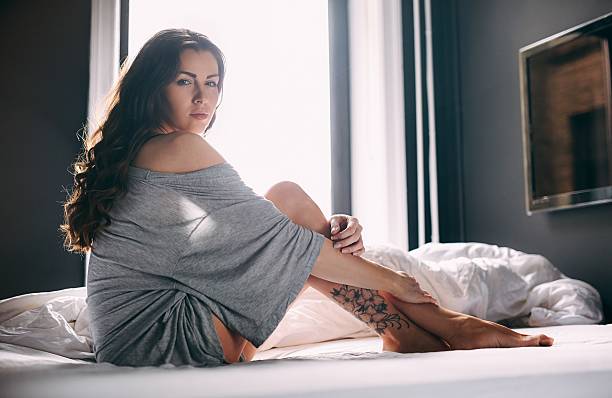 istock Beautiful young lady sitting on bed 513293543
