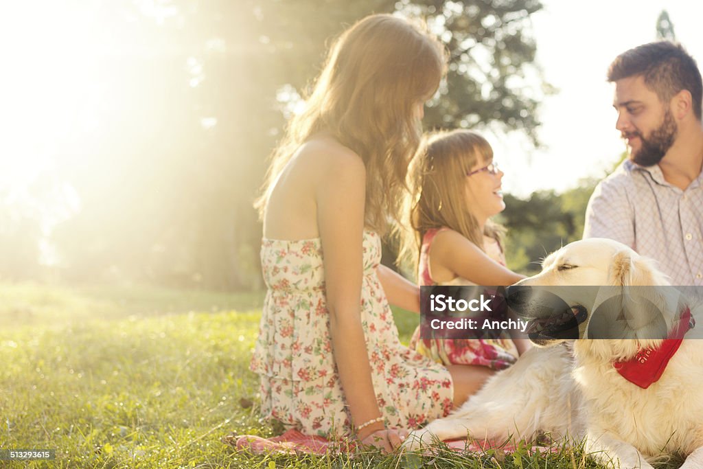 Happy young family on a summer day with their dog Happy young family spending time outdoor on a summer day with their dog Adult Stock Photo