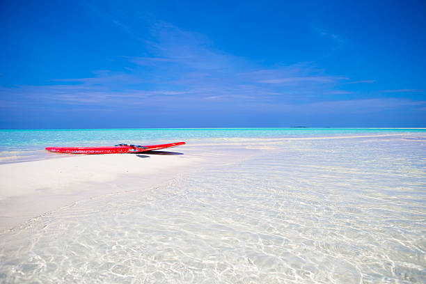 istock Red surfboard on white sandy beach with turquoise water 513295476