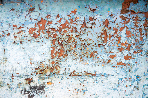 Old rusty metal wall with blue peeling paint