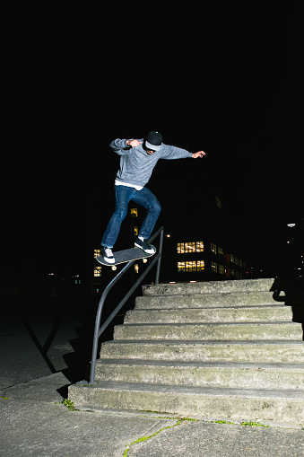 Skateboarding street lifestyle image of a very talented skateboarder skating a street handrail, doing a 