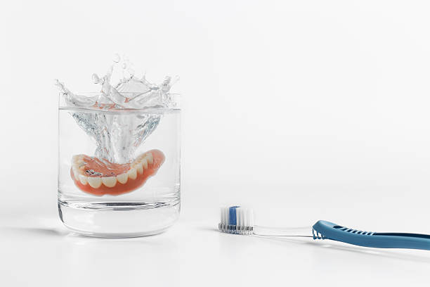 istock Dentures splashing in water with toothbrush 513298190