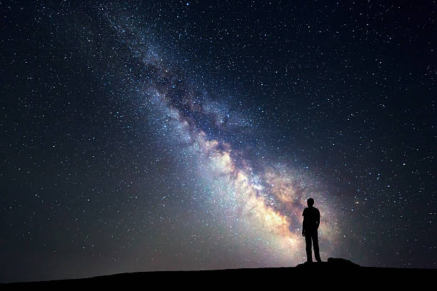 lechoso manera. cielo de noche y silueta de un hombre de pie - milky way star galaxy space fotografías e imágenes de stock