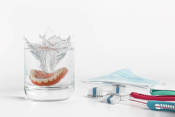 istock Dentures concept with glass, mask and toothbrush 513298348