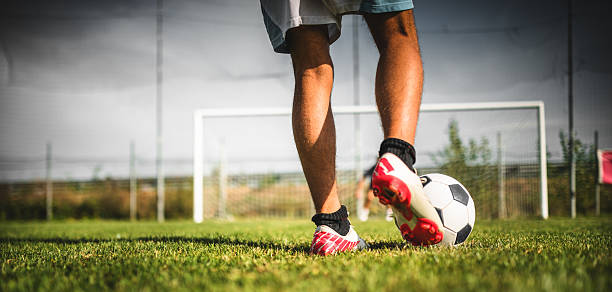 fußballspieler in der gebühr - soccer shoe soccer player kicking soccer field stock-fotos und bilder