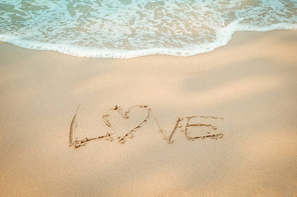 istock Love message hand writing on the sand beach 513305020