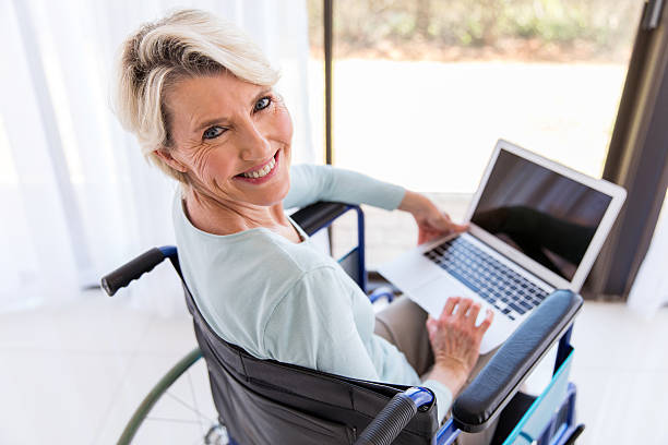 desativado meio envelhecido mulher com computador portátil - looking at camera senior women laptop only women - fotografias e filmes do acervo