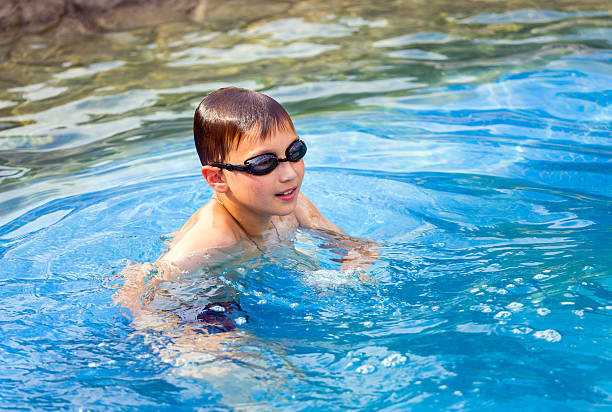 Ten year old boy in swimming pool Ten year old boy with glasses in swimming pool 10 11 years photos stock pictures, royalty-free photos & images