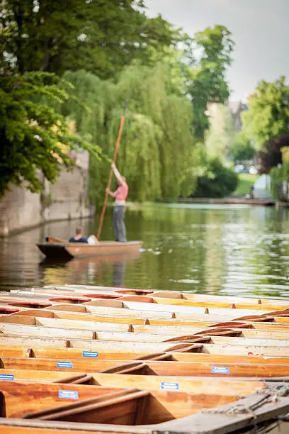 Shallow focus on the foreground punts throws the background Cambridge university buildings and students out of focus in this tranquil English scene.
