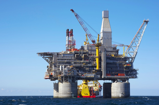 Oil rig and support vessel on offshore area. Blue sky background