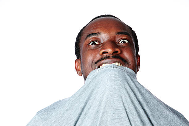 Portrait of crazy young african man biting his t-shirt over white background