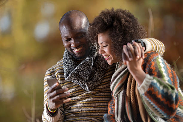 istock Smiling African American couple using mobile phone in nature. 513320786