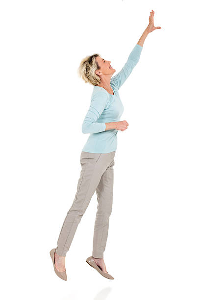 senior woman jumping up and reaching out active senior woman jumping up and reaching out on white background reaching stock pictures, royalty-free photos & images