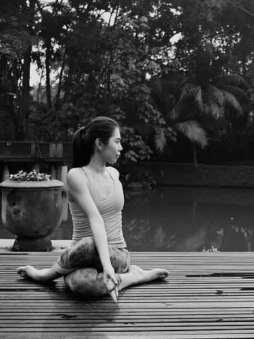Yoga pose by solo Asian female instructor in tropical garden