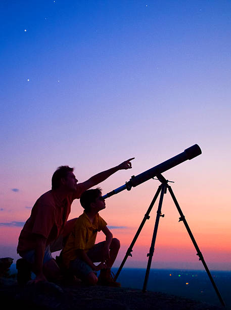 Telescope A young boy looking thru a telescope at sunset with his father. astronomer photos stock pictures, royalty-free photos & images