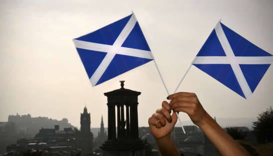 The Scottish flag (saltire) is held aloft on Carlton Hill overlooking the skyline of Edinburgh