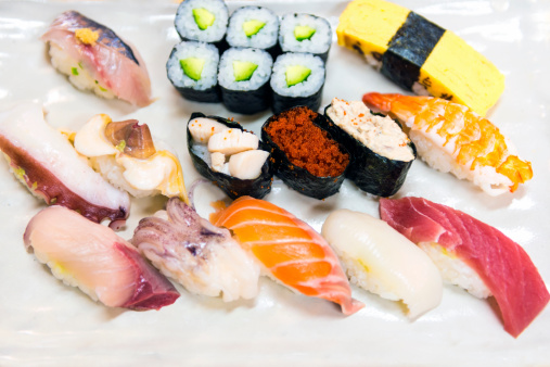 White plate with variety of sushi and sashimi portions. 