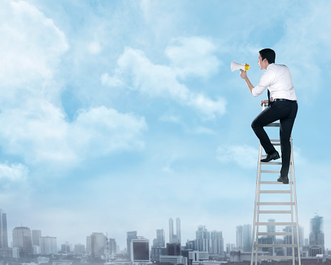Asian business man standing on the ladder, holding megaphone. Leadershop concept