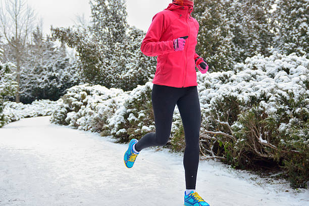 winter laufen im park :  glückliche frau läufer joggen im schnee - snow park road cold stock-fotos und bilder