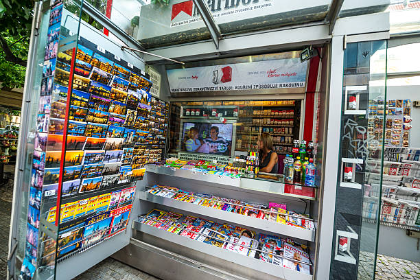 Prague, Czech Republic  - May 8, 2015: Newsstand in Prague, selling magazines, newspapers, snacks, water and cigarettes. Woman vendor inside, waiting for customers.