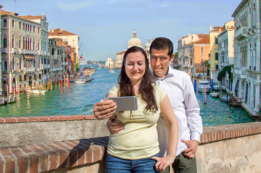 happy couple taking selfie photo in their honeymoon travel in Venice Italy with the grand canal in background