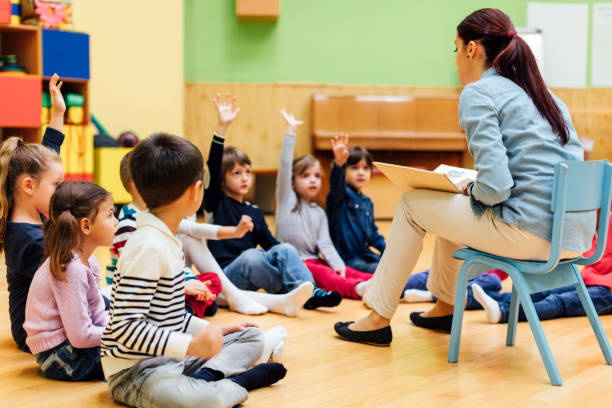 istock Preschool teacher questioning children in classroom. 513373536