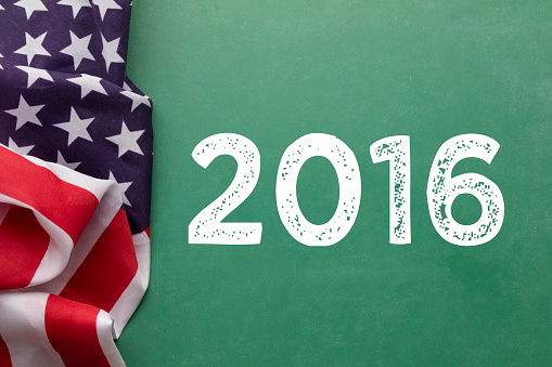 An american stars and stripes flag is laying on a green chalkboard background with white voting message