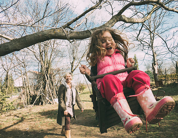 Mother swaying her daughter on a swing