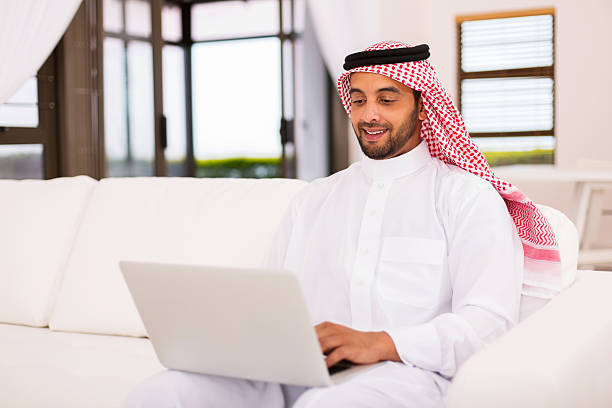 giovane araba " uomo utilizza un computer portatile - ghoutra foto e immagini stock