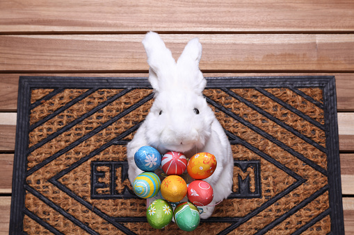 Easter bunny with a bunch of easter eggs on a doormat.