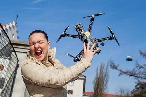 Pretty young woman screams just a moment before drone quadrocopter attack or hit, in the city, on sunny day, space for text