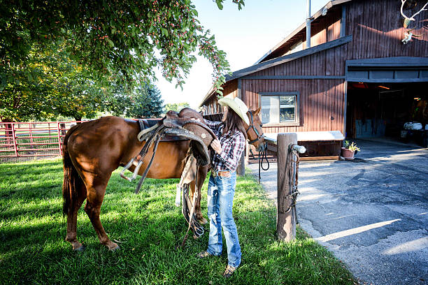 istock Young Woman Saddling a Horse 513380695