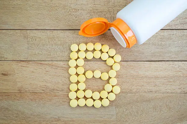 Photo of Yellow pills forming shape to B alphabet on wood background