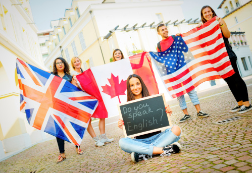 College students learning English with flags and blackboard, outdoors.