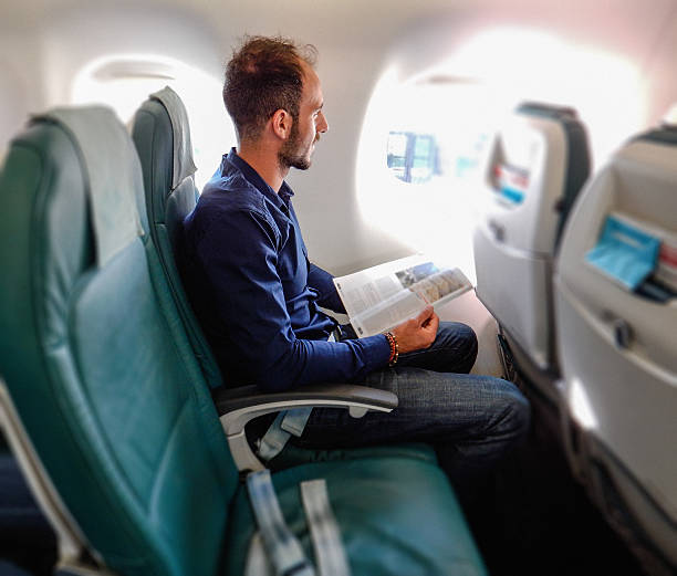 istock man inside an airplane reading a magazine 513382637