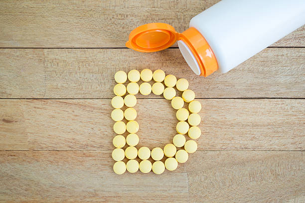 Yellow pills forming shape to D alphabet on wood background Yellow pills forming shape to D alphabet on wood background pellet gun stock pictures, royalty-free photos & images